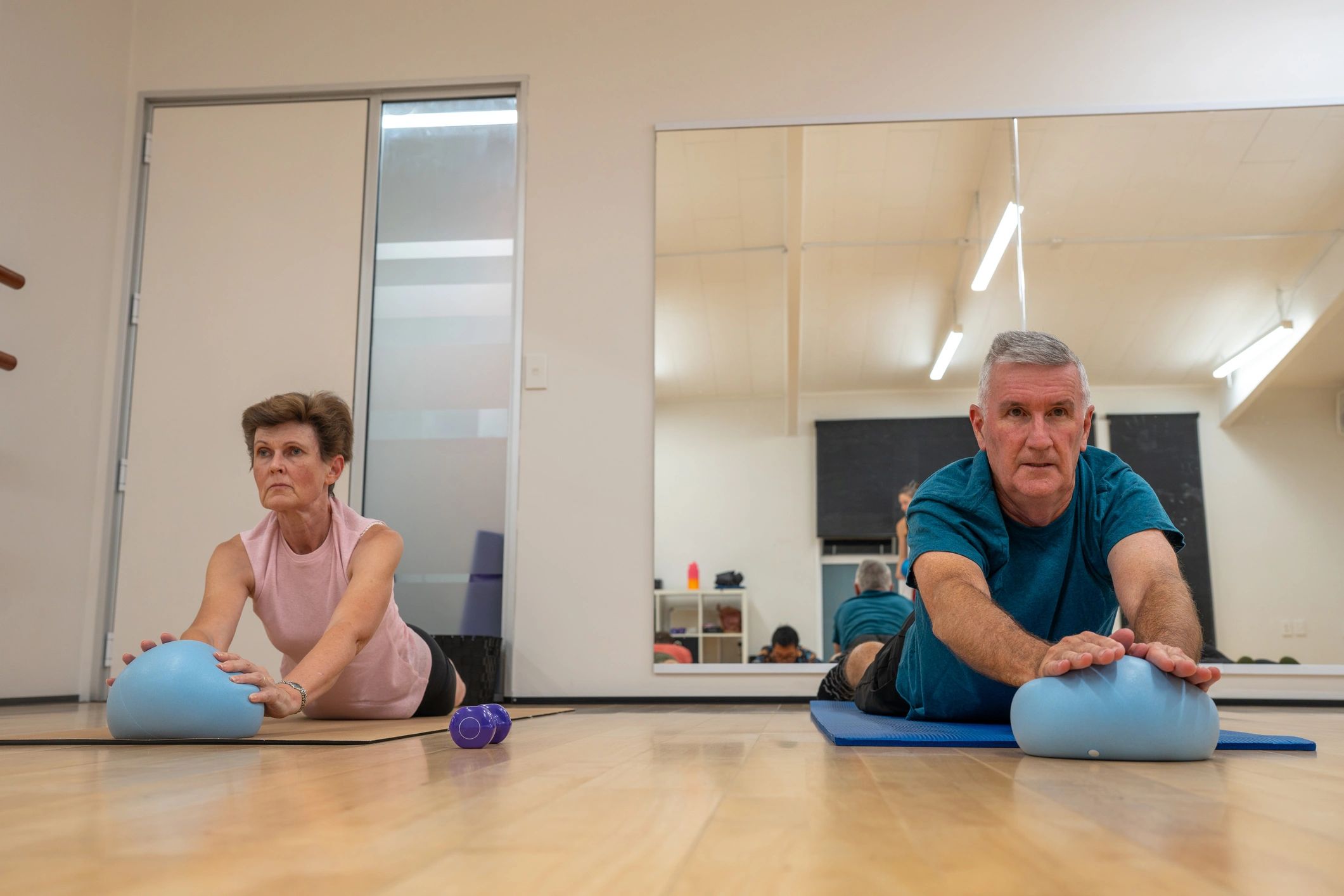 Adults stretching on mats with exercise balls in a fitness class