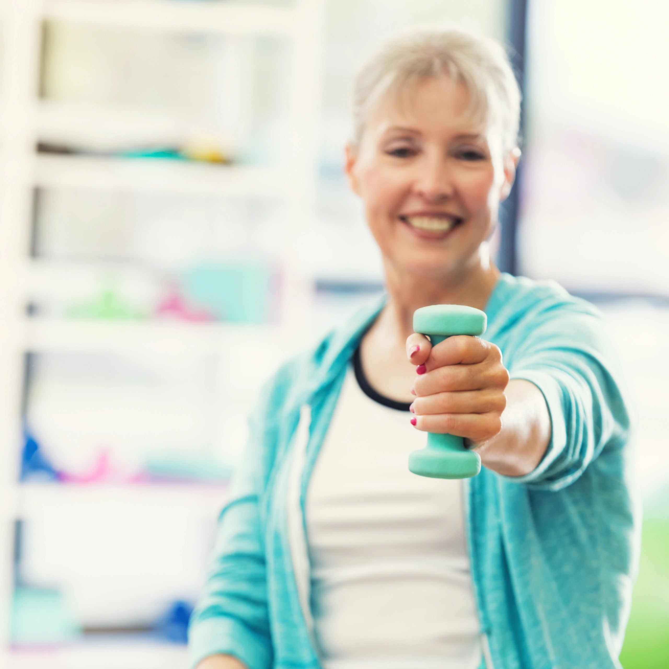 Portrait of a smiling woman holding a barbell toward the camera