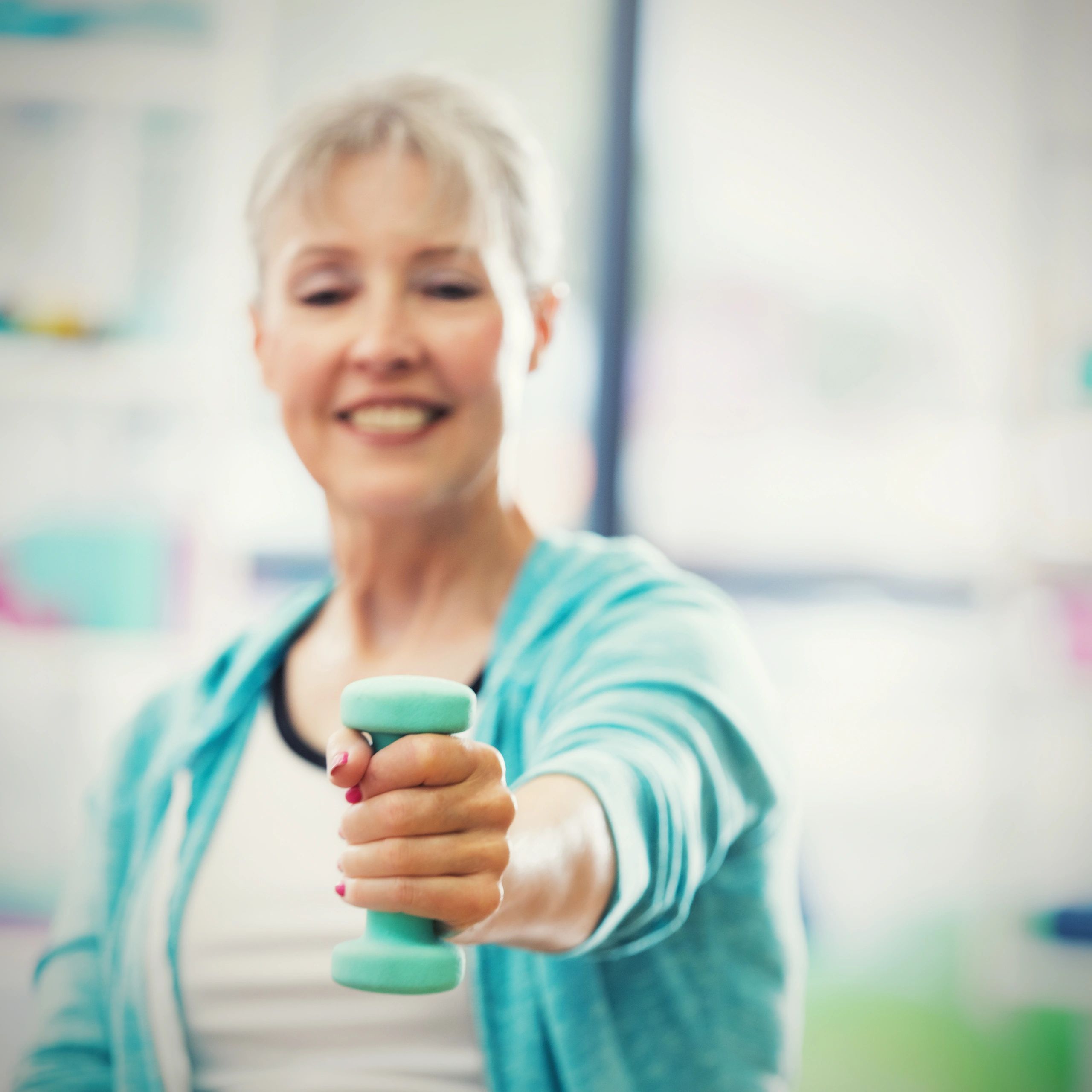 Portrait of a smiling woman lifting a weight at the gym